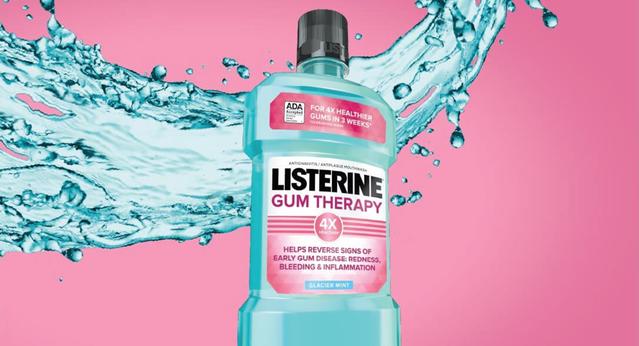 Bottle of Listerine Gum Therapy Antigingivitis Mouthwash in front of a splash of mouthwash