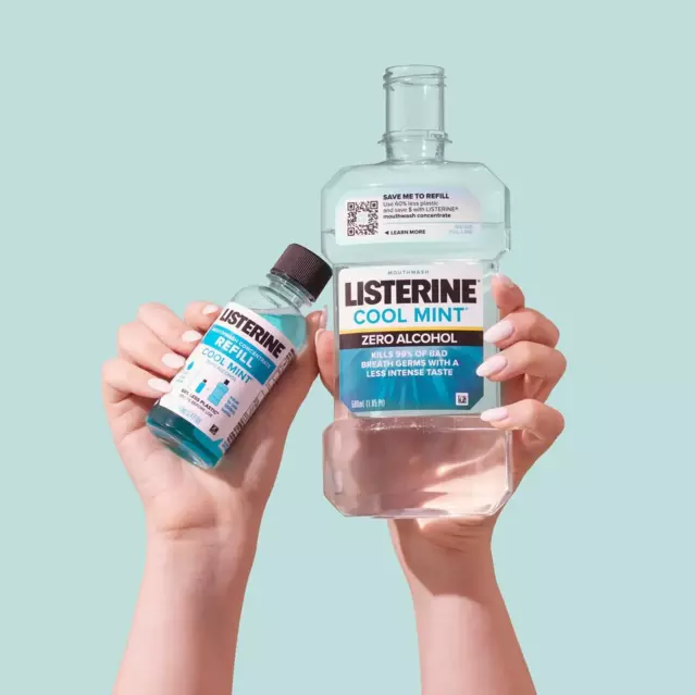 A set of soft feminine hands is holding a Refill Concentrate bottle in one hand and a Listerine Cool Mint Zero Alcohol bottle on the other hand. Behind a light teal background. 