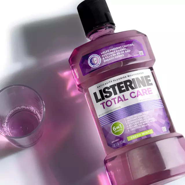 Graphic of Listerine Total Care bottle laid flat on a white counter next to a small glass cup